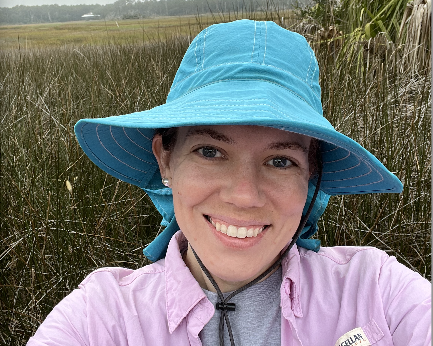 A woman in a blue bucket hat in front of a marsh