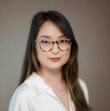 A woman with long brown hair and glasses